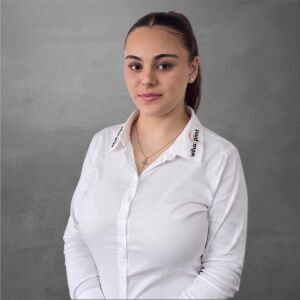Ilona Züger, Technische Verkäuferin Media bei WILUX PRINT, professionell gekleidet in einem weissen Hemd vor einem neutralen Hintergrund.